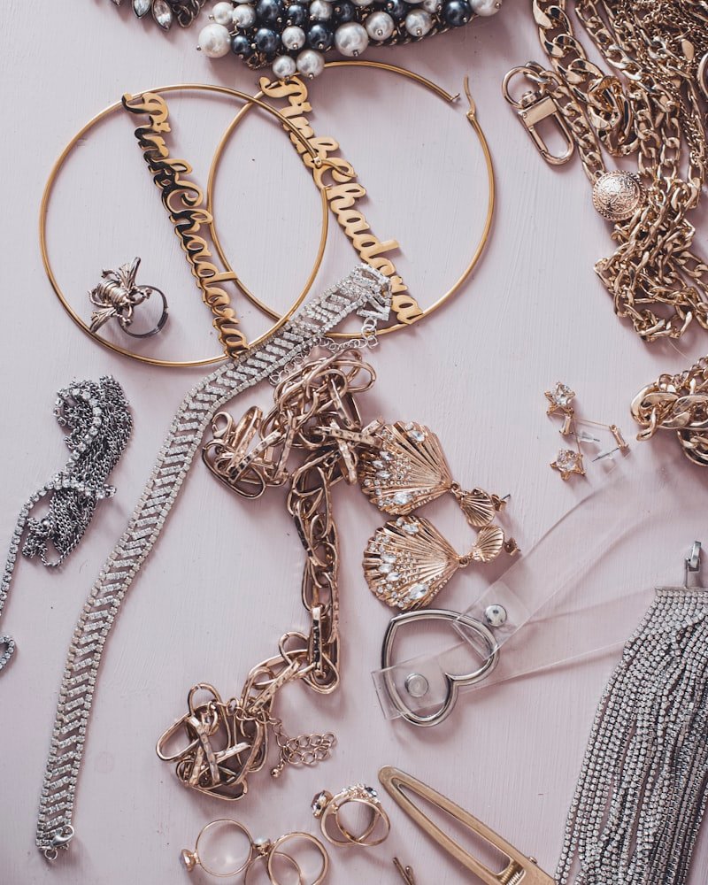 Collection of gold and silver tone hoops, chains and bracelets on a pale surface